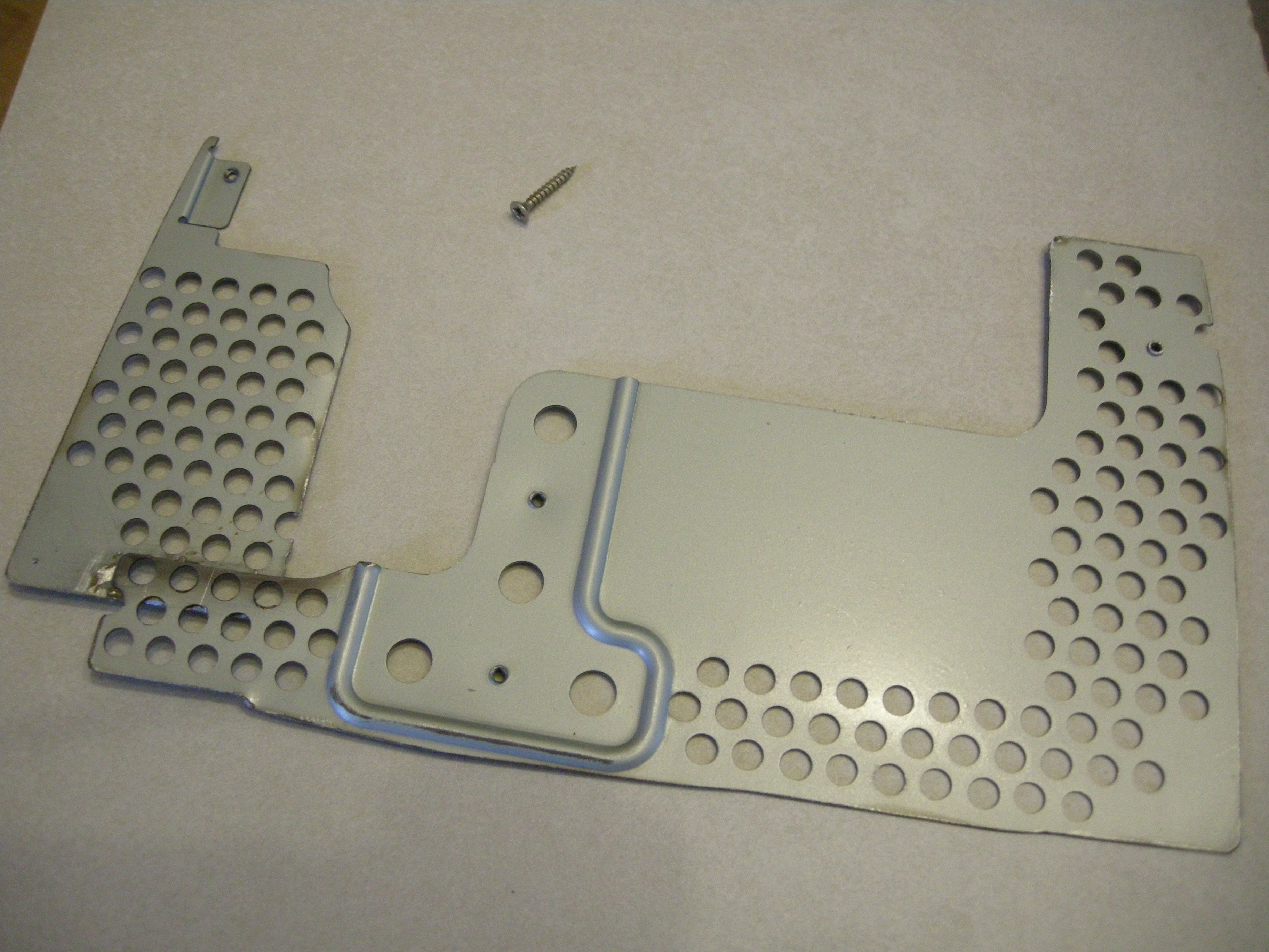 The same soldered grate from Fig. 20 laying on the tile-top, with a small screw next to it